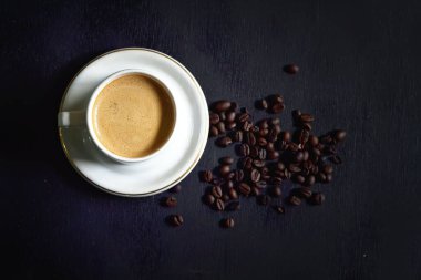 Hot cappuccino and coffee beans on a dark background