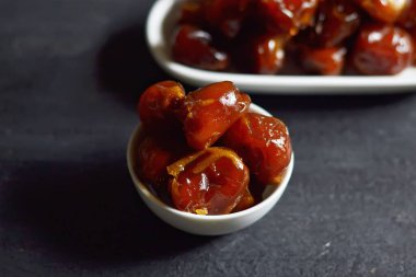 Tahtadaki beyaz bir kasede ıslak hurma.