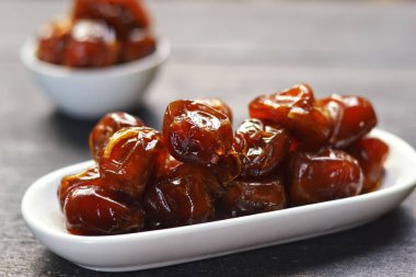 Tahtadaki beyaz bir kasede ıslak hurma.