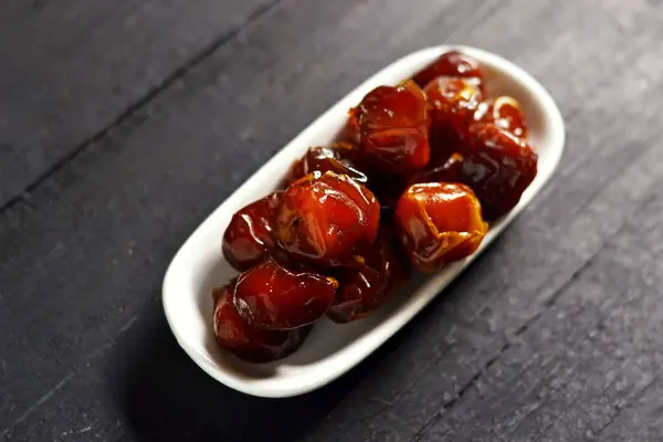 stock image Wet dates in a white bowl on a wooden board