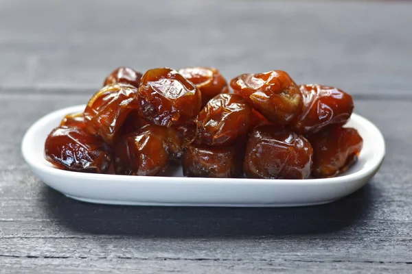 stock image Wet dates in a white bowl on a wooden board