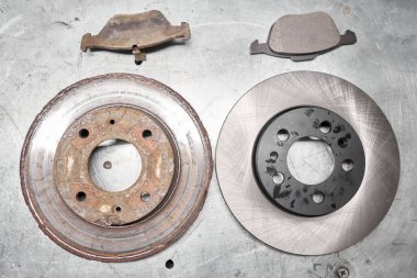 Old rusty brake disc and new disc. Change the old to new brake disc on car in a garage. Auto repair concept