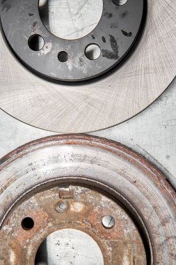 Old rusty brake disc and new disc. Change the old to new brake disc on car in a garage. Auto repair concept