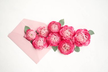 Aşk mektubu. Üzerinde pembe zarf olan beyaz kart. Çiçek yaprakları, güller ve ranunculus. Sevgililer Günü romantik geçmişi. Yüksek kalite fotoğraf