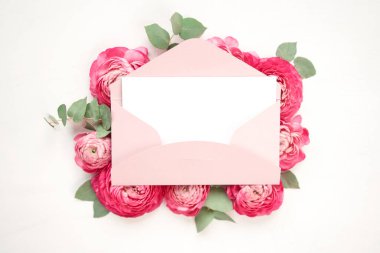 Aşk mektubu. Üzerinde pembe zarf olan beyaz kart. Çiçek yaprakları, güller ve ranunculus. Sevgililer Günü romantik geçmişi. Yüksek kalite fotoğraf