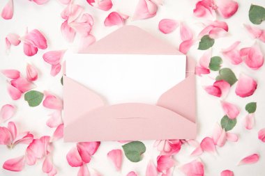 Aşk mektubu. Üzerinde pembe zarf olan beyaz kart. Çiçek yaprakları, güller ve ranunculus. Sevgililer Günü romantik geçmişi. Yüksek kalite fotoğraf