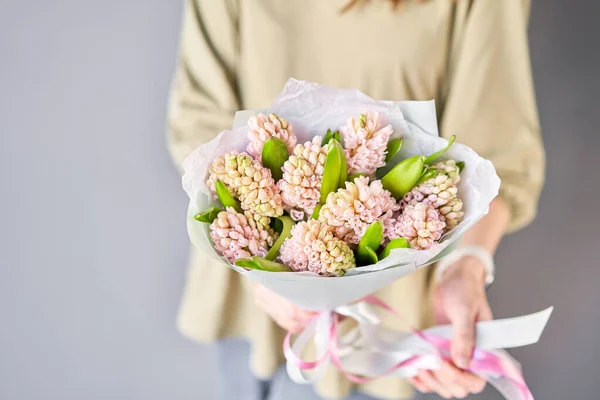 Florist woman creates beautiful bouquet of bouquets of spring pink hyacinths. European floral shop concept. Handsome fresh bunch. Education, master class and floristry courses. Flowers delivery. High