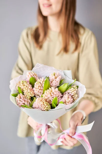 Florist woman creates beautiful bouquet of bouquets of spring pink hyacinths. European floral shop concept. Handsome fresh bunch. Education, master class and floristry courses. Flowers delivery. High