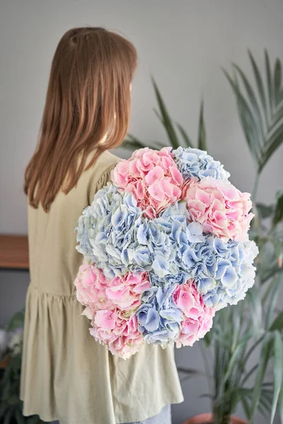 Florist woman creates beautiful bouquet with blue and pink hydrangea. European floral shop concept. Handsome fresh bunch. Education, master class and floristry courses. Flowers delivery.. High