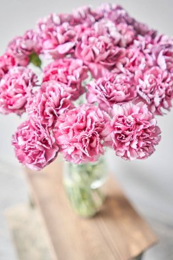 Beautiful pink carnation flowers in a vase on a table . Bouquet of light pink flower. Decoration of home. Wallpaper and background. 