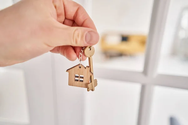 Concept of renting an apartment. House key in man hand. Young man. Modern light lobby interior. Real estate, hypothec, moving home or renting property. High quality photo