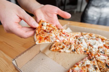 Closeup hand of chef baker in uniform blue apron cutting pizza at kitchen. High quality photo clipart