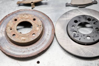 Old rusty brake disc and new disc. Change the old to new brake disc on car in a garage. Auto repair concept
