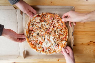 Closeup hand of chef baker in uniform blue apron cutting pizza at kitchen. High quality photo