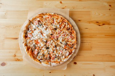 Closeup hand of chef baker in uniform blue apron cutting pizza at kitchen. High quality photo
