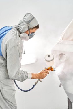 Arabanın arka kapısını boyuyordun. Özel boya odasında, kostüm ve koruyucu kıyafetler giymiş bir araba boyacısı. Araba servis istasyonu. Kazadan sonra araba tamiri..