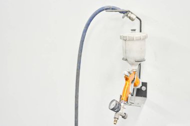 Sprey tabanca görüntüsü. İşçi, arabanın parçalarını özel boya odasına boyuyor, kostüm ve koruyucu giysiler giyiyor. Araba servis istasyonu.