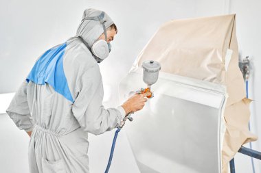 Arabanın arka kapısını boyuyordun. Özel boya odasında, kostüm ve koruyucu kıyafetler giymiş bir araba boyacısı. Araba servis istasyonu. Kazadan sonra araba tamiri..