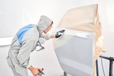 Arabanın arka kapısını boyuyordun. Özel boya odasında, kostüm ve koruyucu kıyafetler giymiş bir araba boyacısı. Araba servis istasyonu. Kazadan sonra araba tamiri..