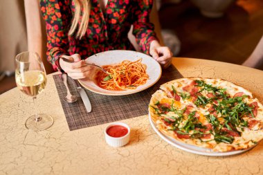 Kadın domatesli İtalyan makarnası yiyor, et yiyor. Yakın plan spagetti bolonezi kaşıkla bir çatalın etrafına sarıyor. Parmesan peyniri.
