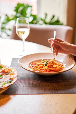 Kadın domatesli İtalyan makarnası yiyor, et yiyor. Yakın plan spagetti bolonezi kaşıkla bir çatalın etrafına sarıyor. Parmesan peyniri.