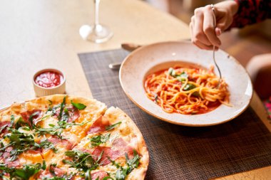 Kadın domatesli İtalyan makarnası yiyor, et yiyor. Yakın plan spagetti bolonezi kaşıkla bir çatalın etrafına sarıyor. Parmesan peyniri.