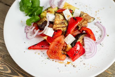 Yunan salatası, peynirli sebze. Izgara sebze, patlıcan, kırmızı biber, soğan. Kırsal bir masada ahşap bir tahtada servis yapmak. Barbekü restoran menüsü.