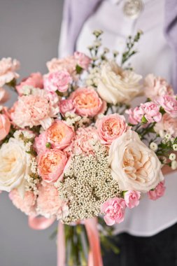 Wicker sepetinde çiçek aranjmanı. Kadın elinde güzel bir buket karışık çiçek. Güzel, taze bir buket. Küçük çiçekçi ve çiçek teslimatı.