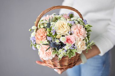 Wicker sepetinde çiçek aranjmanı. Kadın elinde güzel bir buket karışık çiçek. Güzel, taze bir buket. Küçük çiçekçi ve çiçek teslimatı.