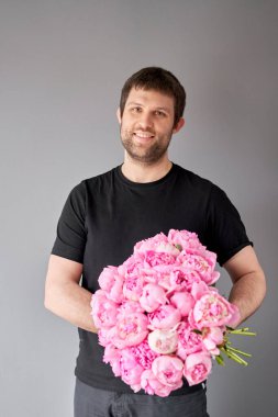 Pembe melek yanakları bir erkeğin elinde şakayıklar. Katalog ya da internet mağazası için güzel şakayık çiçekleri. Çiçek dükkanı konsepti. Taze kesilmiş güzel bir buket. Çiçek teslimatı.