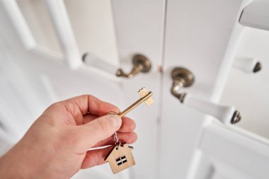 Concept of renting an apartment. House key in man hand. Young man. Modern light lobby interior. Real estate, hypothec, moving home or renting property. High quality photo