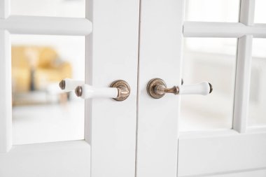 Old-style door, white - handle close up. The interior of a bright living room in a modern apartment. High quality photo