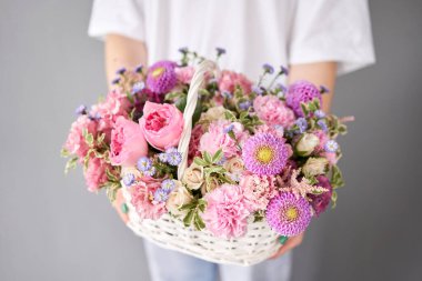 Wicker sepetinde çiçek aranjmanı. Kadın elinde güzel bir buket karışık çiçek. Güzel, taze bir buket. Küçük çiçekçi ve çiçek teslimatı.