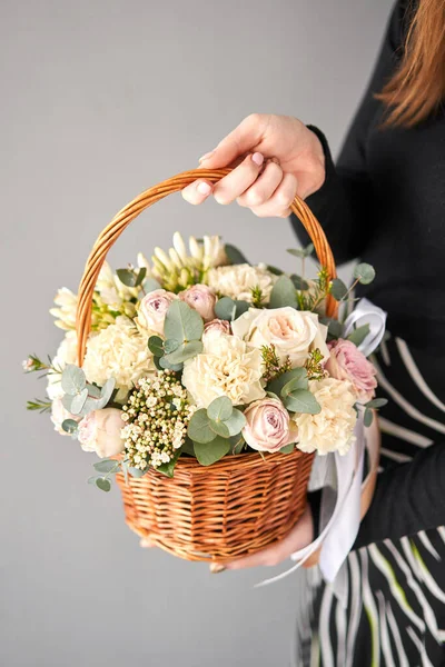 Small flower shop and Flowers delivery. Flower arrangement in Wicker basket. Beautiful bouquet of mixed flowers in woman hand. Handsome fresh bouquet.