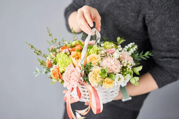 Small flower shop and Flowers delivery. Flower arrangement in Wicker basket. Beautiful bouquet of mixed flowers in woman hand. Handsome fresh bouquet.