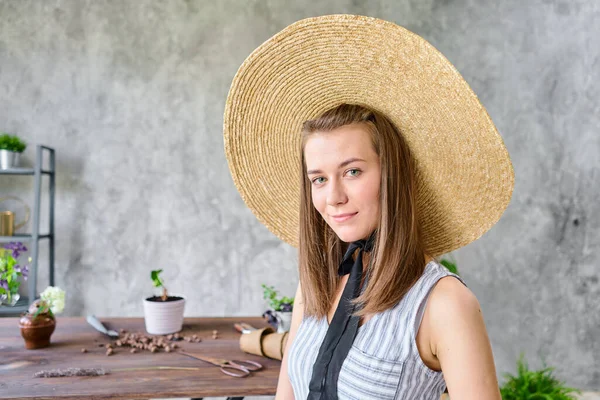 肖像画の若い女性は広いつばのわらの帽子をかぶっていた 庭師は植物を移植する ホームガーデンの概念 花と庭の店 高品質 — ストック写真
