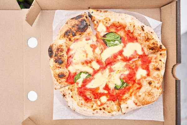 stock image Pizza delivery concept. Baking in a cardboard box on a wooden background. Baked a delicious pizza Margarita in a traditional wood-burning oven in a Neapolitan restaurant, Italy. High quality photo