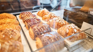 Pastanenin vitrininde çeşitli taze hamur işleri var. Bademli kruvasan bir kafede diğer hamur işlerinin yanında taze ve sıcaktır. Bir İtalyan restoranının içi. Yüksek kalite fotoğraf