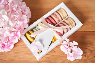 Mevcut kutuda Fransız makarnası var. Çiçek arkaplanda tatlı bir tatlı. Makarna kekleri ve farklı çiçeklerle dolu bir hayat. Teslimat konsepti, kahve ve çiçekçi. Yüksek kalite fotoğraf