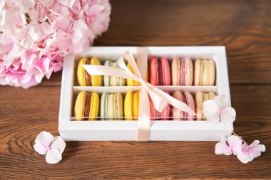 Mevcut kutuda Fransız makarnası var. Çiçek arkaplanda tatlı bir tatlı. Makarna kekleri ve farklı çiçeklerle dolu bir hayat. Teslimat konsepti, kahve ve çiçekçi. Yüksek kalite fotoğraf