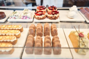 Pastanede taze böğürtlen ve kremalı lezzetli tatlıların olduğu bir vitrin. Çikolatayla kaplanmış ve fıstıklı kremayla süslenmiş çeşitli kekler. - Evet. Yüksek kalite fotoğraf