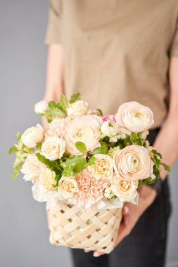 Wicker sepetinde çiçek aranjmanı. Kadın elinde güzel bir buket karışık çiçek. Çiçek dükkanı konsepti. Güzel, taze bir buket. Çiçek teslimatı. Yüksek kalite fotoğraf
