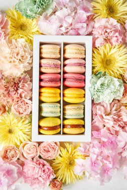 Mevcut kutuda Fransız makarnası var. Çiçek arkaplanda tatlı bir tatlı. Makarna kekleri ve farklı çiçeklerle dolu bir hayat. Teslimat konsepti, kahve ve çiçekçi. Yüksek kalite fotoğraf