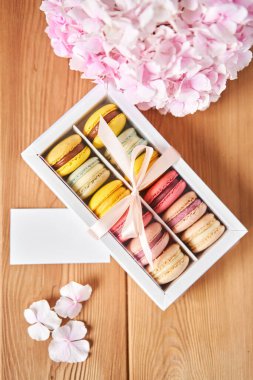 Mevcut kutuda Fransız makarnası var. Çiçek arkaplanda tatlı bir tatlı. Makarna kekleri ve farklı çiçeklerle dolu bir hayat. Teslimat konsepti, kahve ve çiçekçi. Yüksek kalite fotoğraf