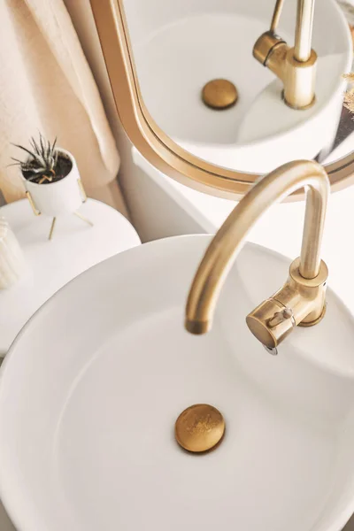 一个漂亮的水池 有一个金色水龙头 旁边是一个椭圆形的镜子和一个架子与手巾 在浴室水池里的精致的金色水龙头的特写 旁边是时尚的装饰 高质量的照片 — 图库照片