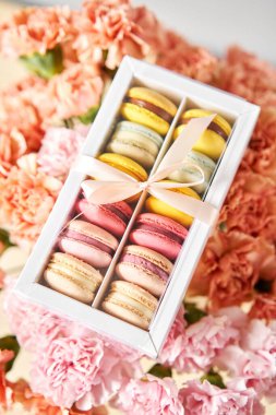 Mevcut kutuda Fransız makarnası var. Çiçek arkaplanda tatlı bir tatlı. Makarna kekleri ve farklı çiçeklerle dolu bir hayat. Teslimat konsepti, kahve ve çiçekçi. Yüksek kalite fotoğraf