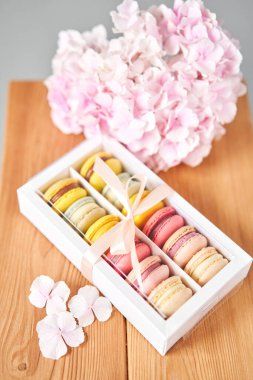 Mevcut kutuda Fransız makarnası var. Çiçek arkaplanda tatlı bir tatlı. Makarna kekleri ve farklı çiçeklerle dolu bir hayat. Teslimat konsepti, kahve ve çiçekçi. Yüksek kalite fotoğraf