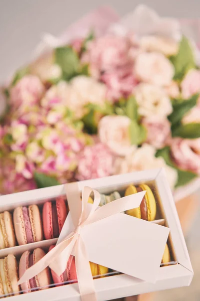 stock image Dessert French Macarons in present box. Sweet dessert on a flowers background. Still life with macaroni cakes and different flower. Delivery concept, coffee and flower shop. High quality photo