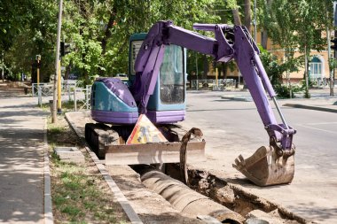 Büyük matkap matkabı yolu. Ağır makineler, fırtına suyu giderlerini onarmak için asfaltı eziyor. Kazı makinesi suda izler bırakmış. Bir yolun tamiri ve genişletilmesi. Yüksek kalite fotoğraf