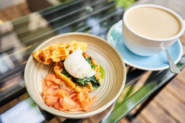  Kız haşlanmış yumurta keser ve yumurta sarısı akar. Patates waffle 'ı, somon ve yumurtalı avokado kreması. Sağlıklı kahvaltı, protein. Restoran yemeği. Hareketi Durdur